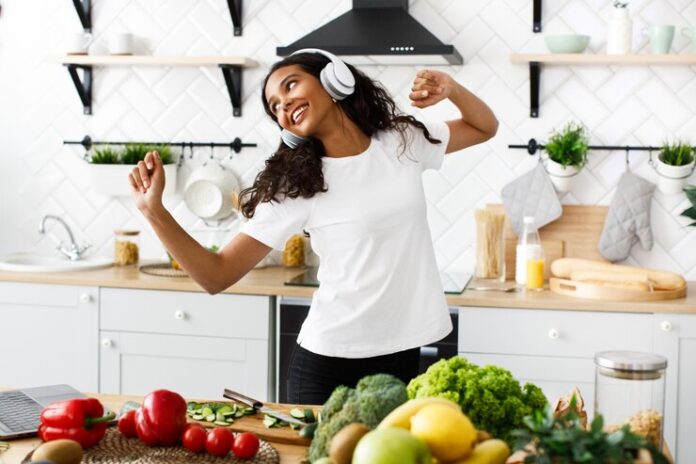sorriu-mulata-em-grandes-fones-de-ouvido-sem-fio-esta-dancando-perto-de-mesa-cheia-de-legumes-e-frutas_8353-10296